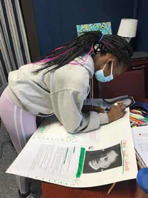 Photo of Lincoln student creating a poster with facts about Charles R. Drew.